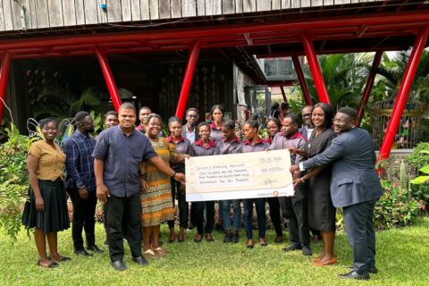 DEI-and-Fidelity-Bank-staff-stand-together-holding-a-dummy-cheque-with-the-beneficiary-students.-1