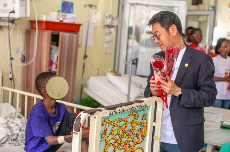 The Managing Director of Vivo Energy Ghana, Mr. Christian Li presenting chocolate and a rose flower to a patient in the children's ward.